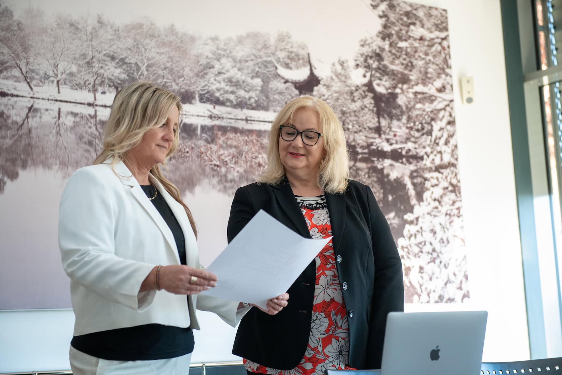Two female staff members are discussing some documents