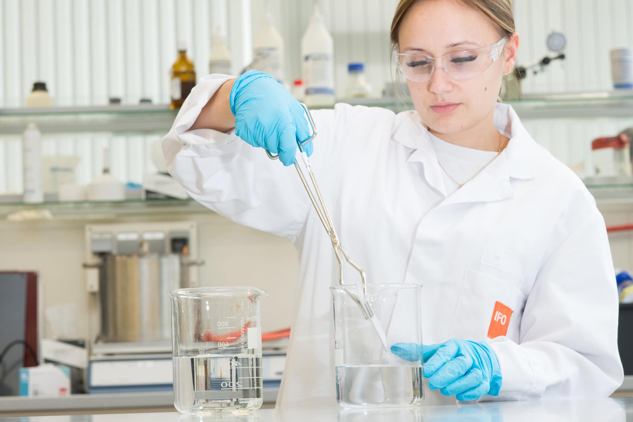 A laboratory technician immerses an anodised sample in acid for the abrasion test