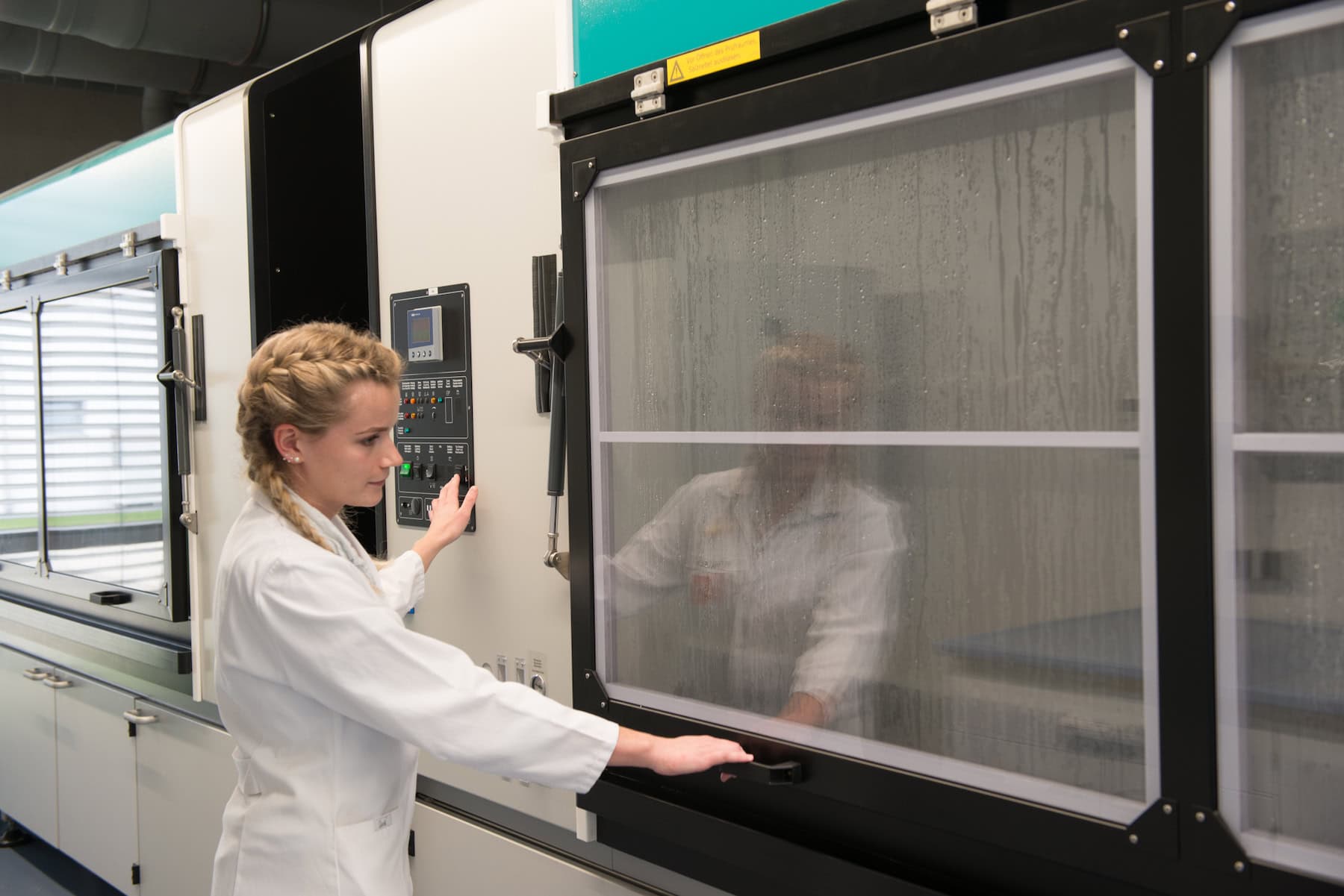 A laboratory technician opens a salt spray chamber