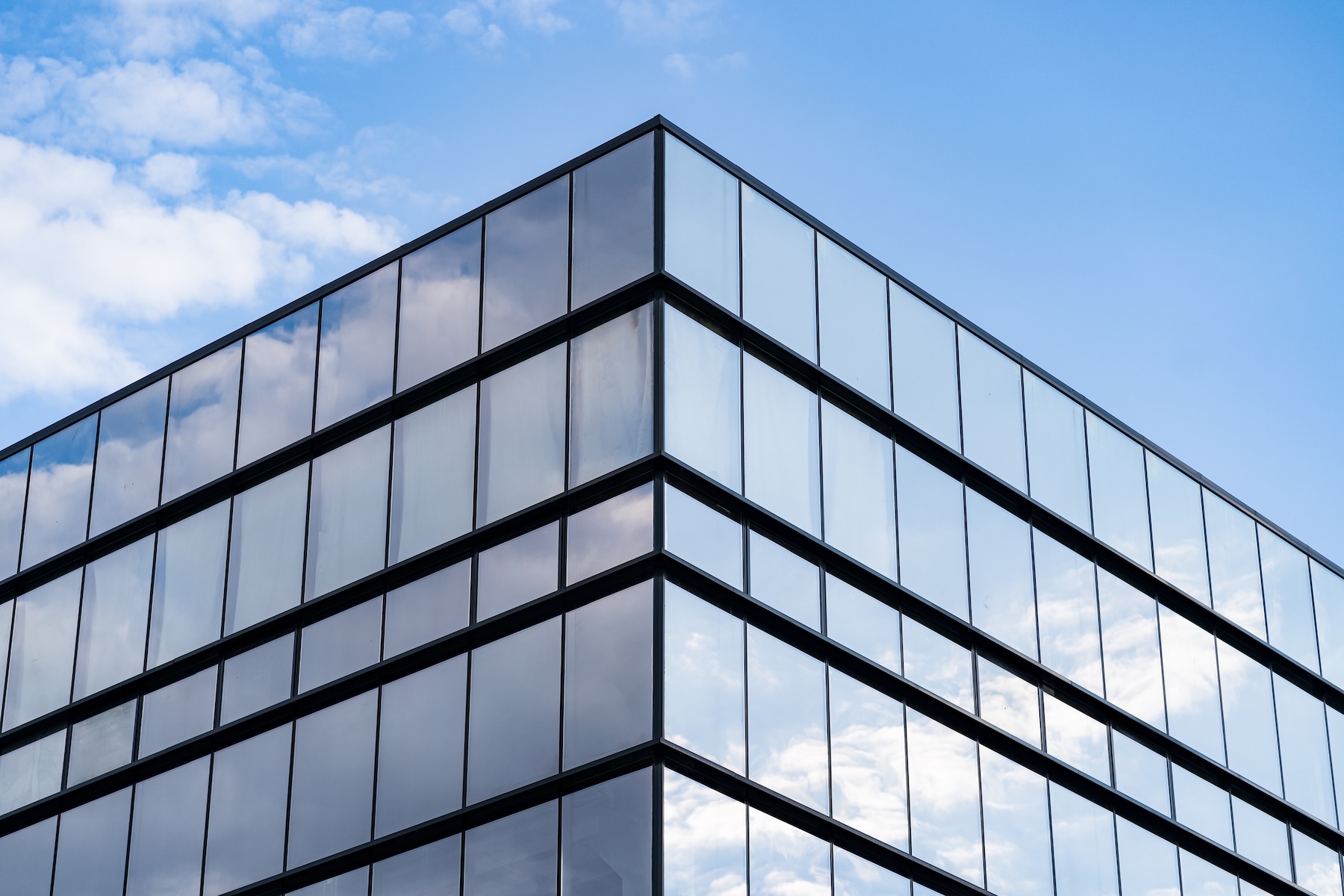 The glass façade of an office block against a blue sky